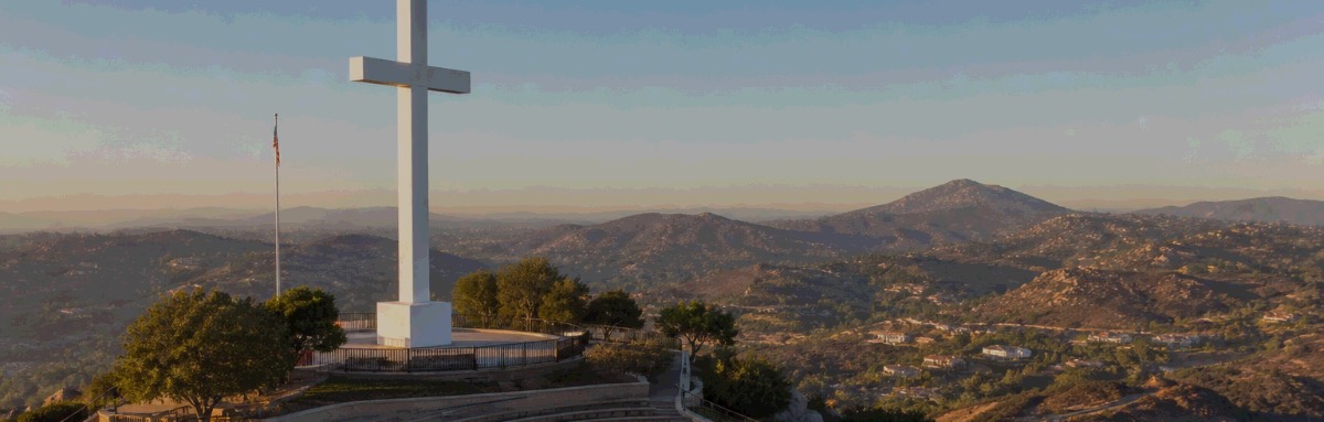 A hilltop cross above the East County hills at sunrise